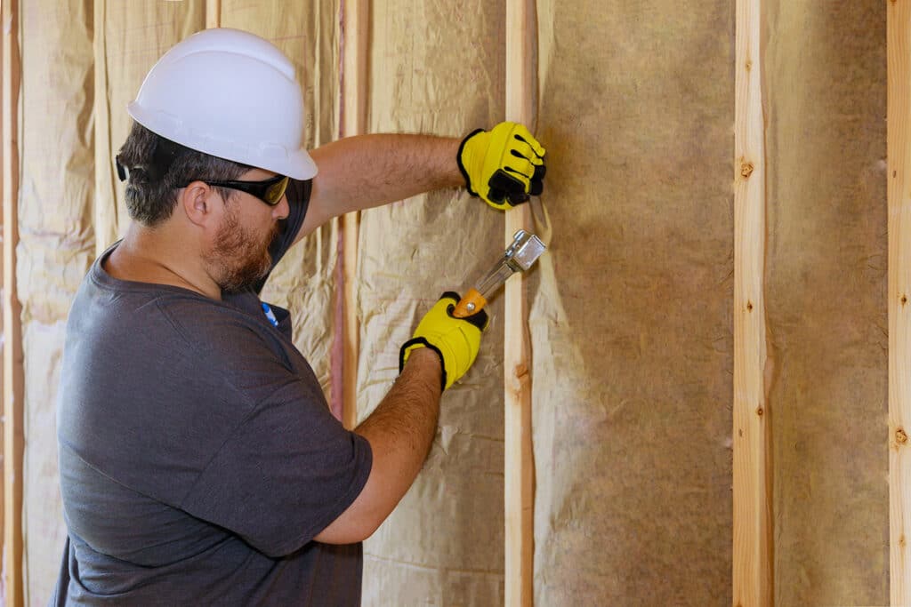 Image of worker installing fiberglass insulation