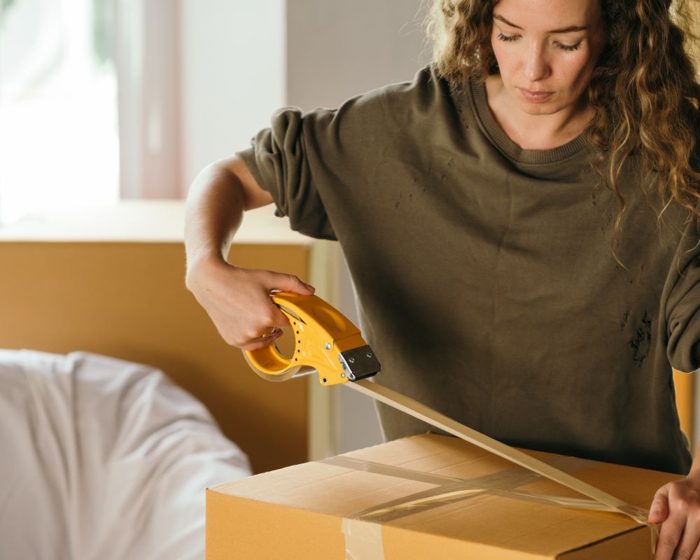 Woman taping box as part of estate closing using dumpster rental